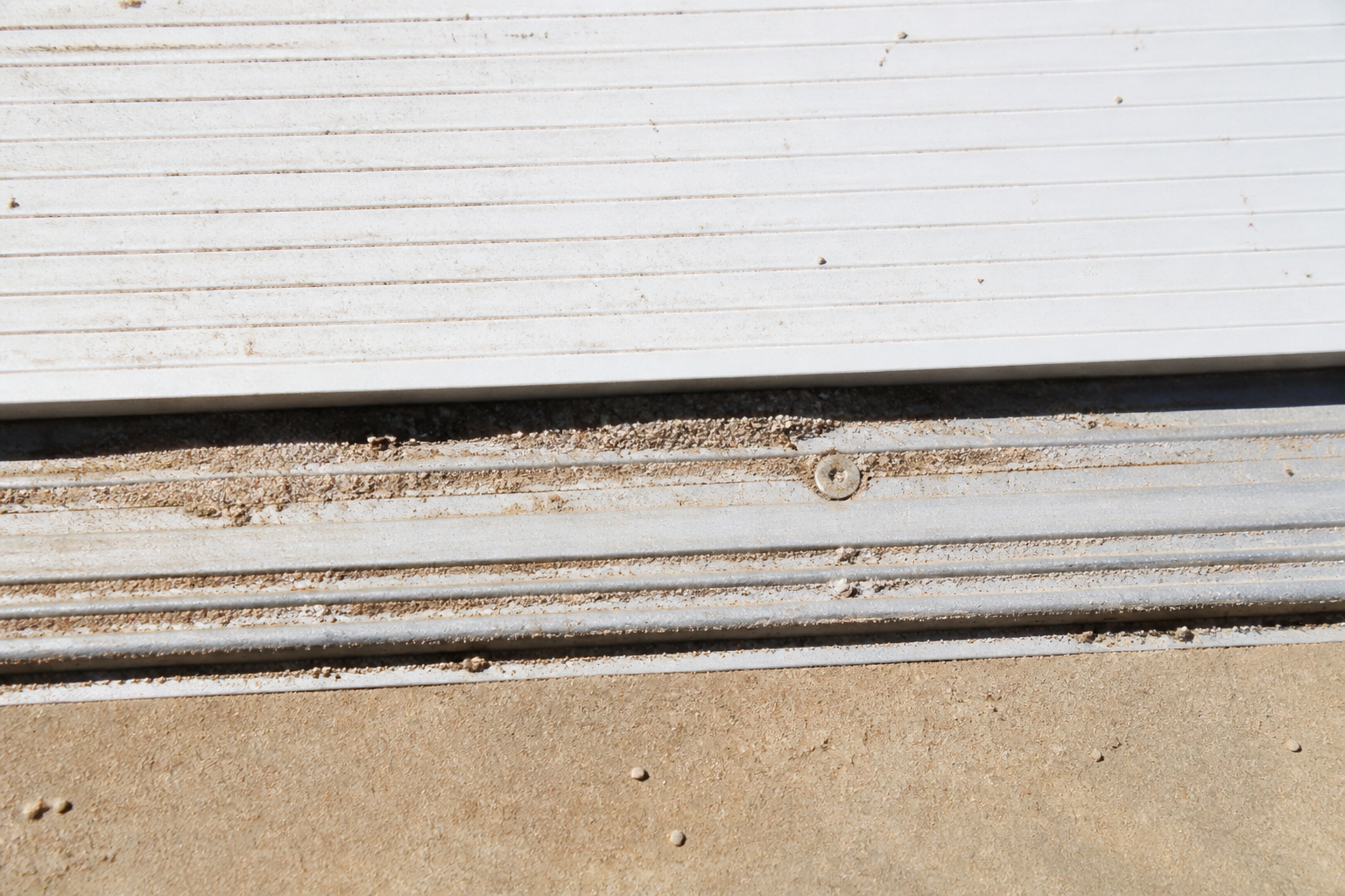 Dust collected along a pool cover track in bright sun
