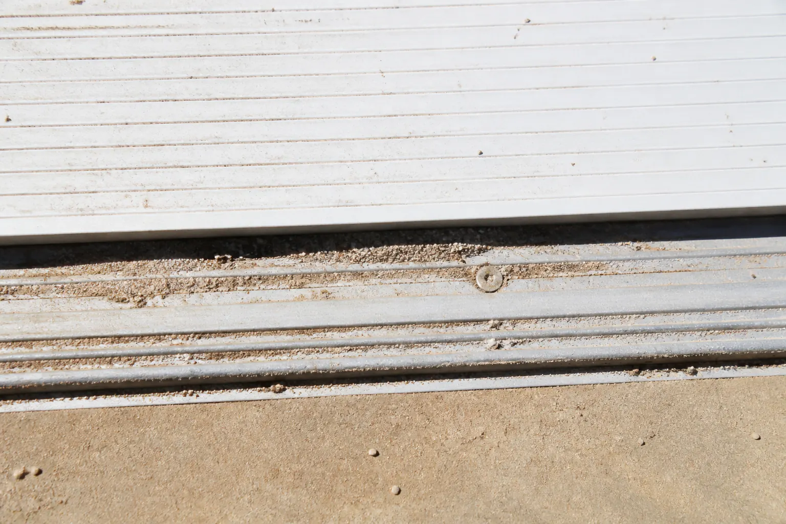 Dust collected along a pool cover track in bright sun