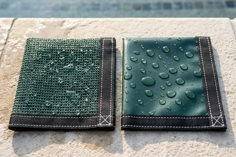 Close-up comparison of porous woven mesh pool safety cover fabric and coated solid vinyl pool safety cover fabric with black webbing straps