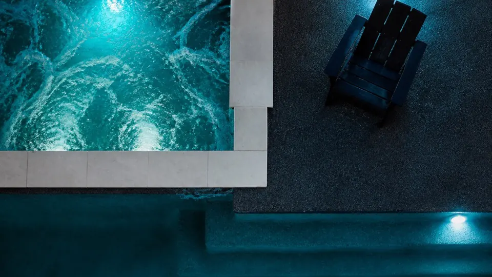 Finished rectangular pool and spa lit from below at night